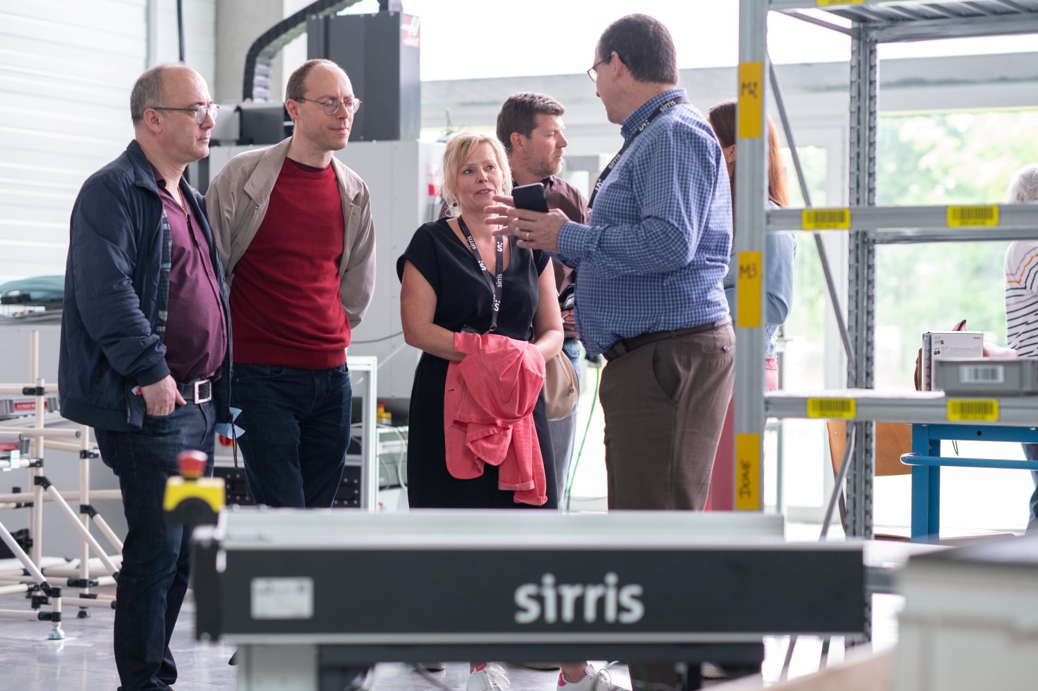 Sirris expert legt productiestrategie uit aan een groep bezoekers in het Sirris Lab bij Facthory in Genk, met een AMR op de voorgrond