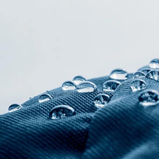 Close-up van waterdruppels op een hydrofobe en oleofobe textieloppervlakte, illustrerend het doel van het BIOSUPHYOL-industrieel onderzoeksproject naar biogebaseerde en PFAS-vrije coatings.