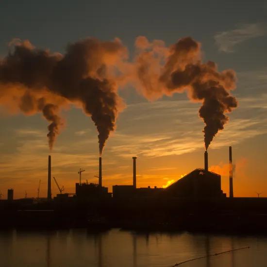 Low angle shot of a factory with smoke and steam coming out of the chimneys captured at sunset