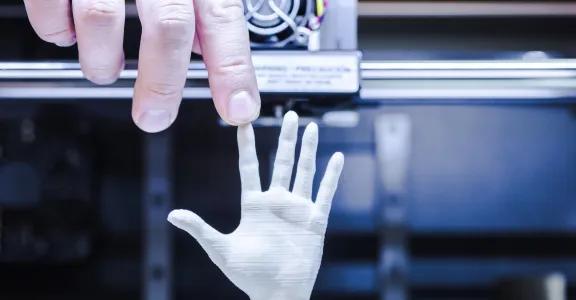 Male hand touching finger of 3D printed hand under D o