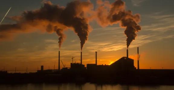 Low angle shot of a factory with smoke and steam coming out of the chimneys captured at sunset