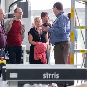 Sirris expert legt productiestrategie uit aan een groep bezoekers in het Sirris Lab bij Facthory in Genk, met een AMR op de voorgrond