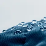 Close-up of water droplets on a hydrophobic and oleophobic textile surface, illustrating the goal of the BIOSUPHYOL industrial research project on bio-based and PFAS-free coatings.